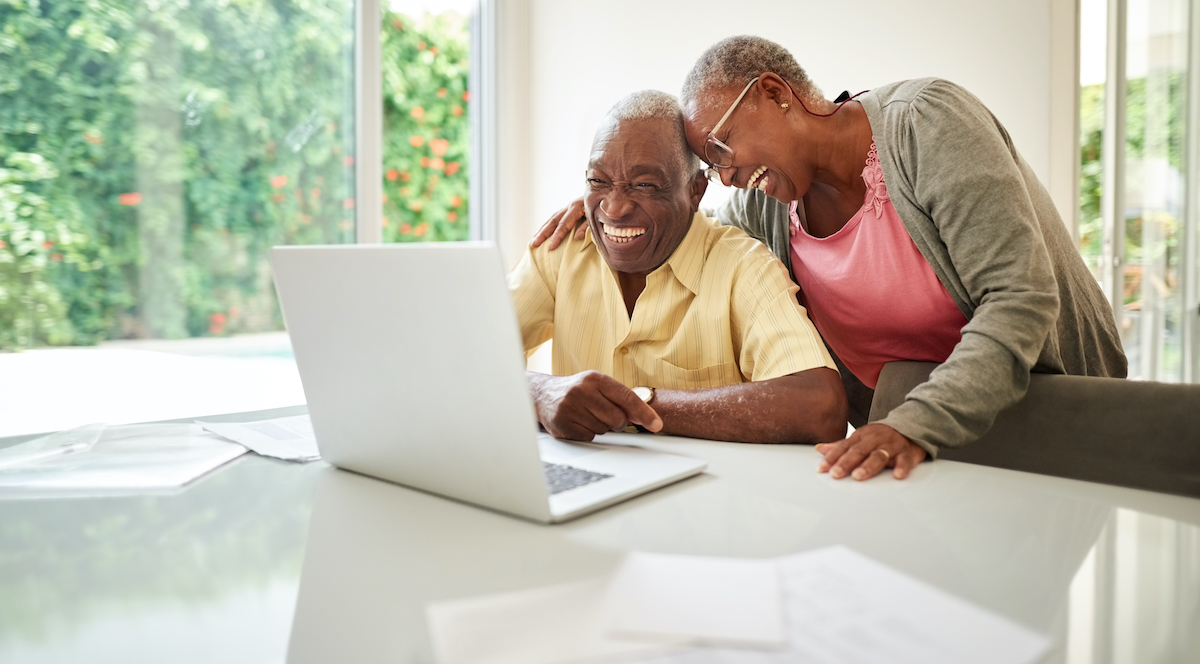 Senior couple smiling looking at a laptop together