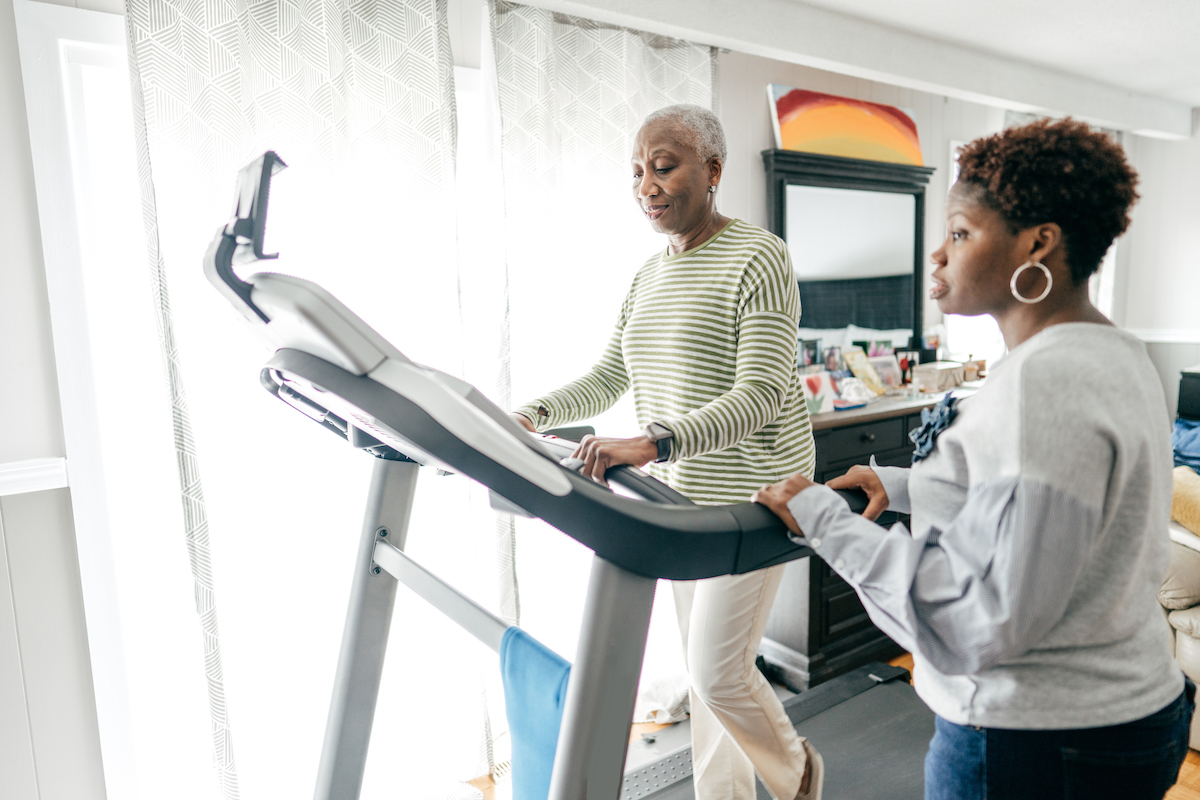 Senior woman on a treadmill and caregiver nearby
