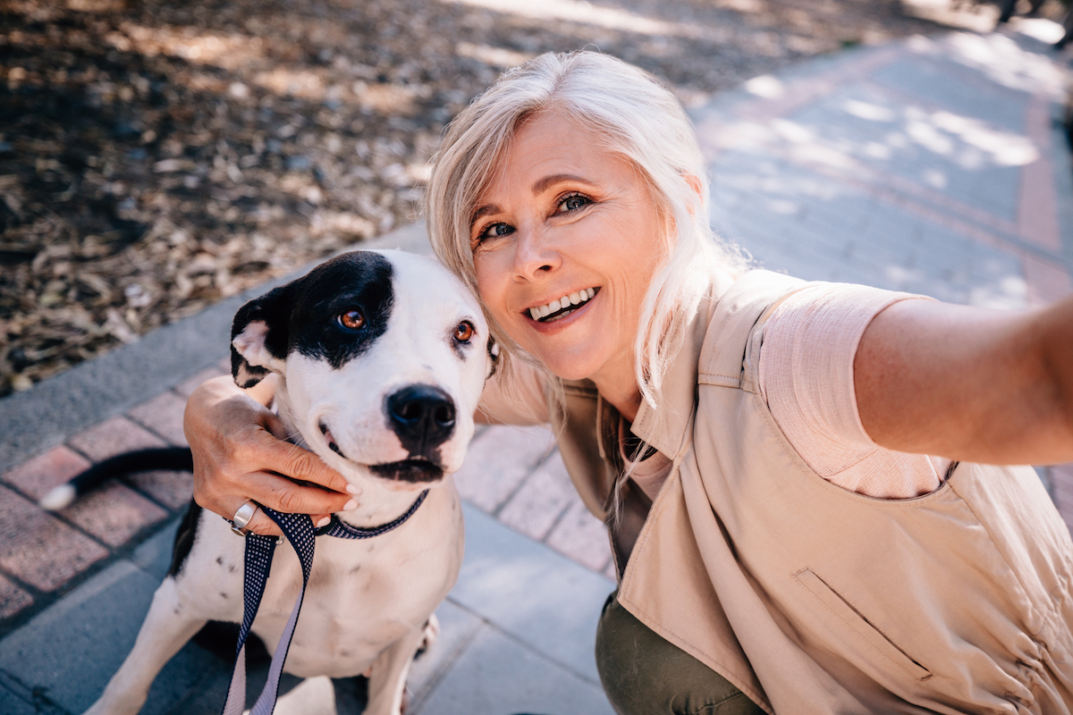 Smiling senior woman taking selfies with pet dog in park