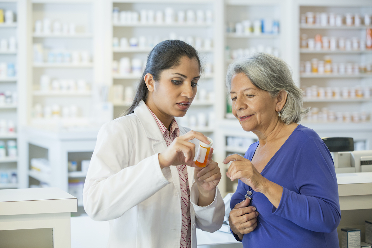 Farmacéutica hablando con una clienta de la tercera edad
