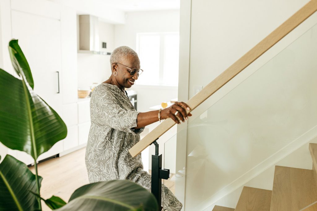 senior woman climbing the stairs at home for a room by room guide to preventing falls