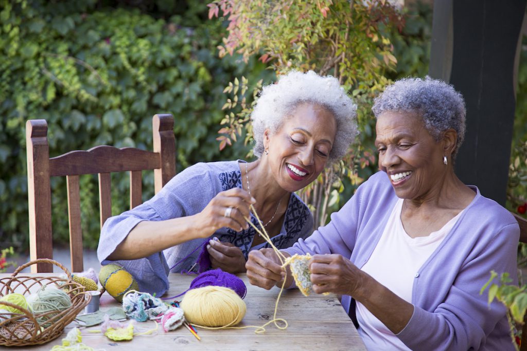 two senior Black women knitting for a story on chronic loneliness