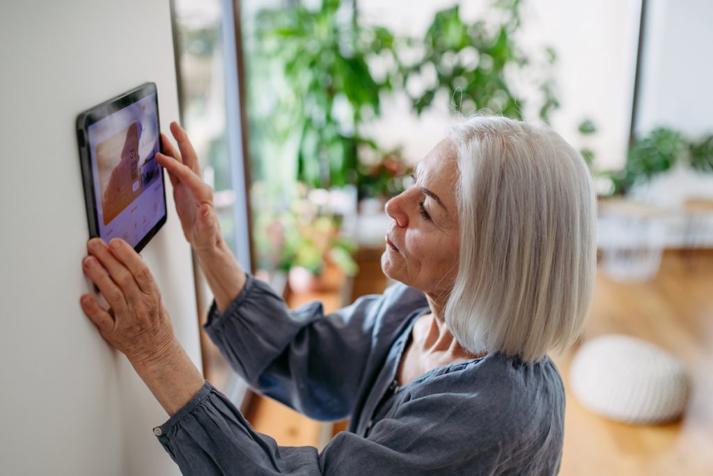 Senior woman adjusting smart technology at home